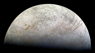 A hemisphere of Jupiter's moon Europa, which looks white with criss-crossed dark cracks.